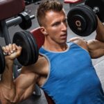 Man in black tank top performing dumbbell curl with text overlay reading 'Dumbbell Only Workout: 5 Day Dumbbell Workout Split' on dark background.